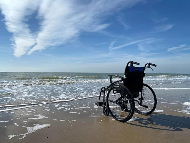 Wheelchair on beach in front of waves