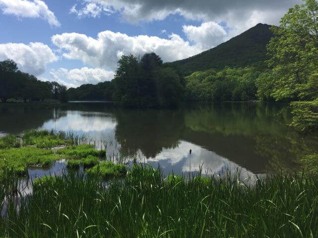 lake reflecting the sunlight and clouds in front of a mountain