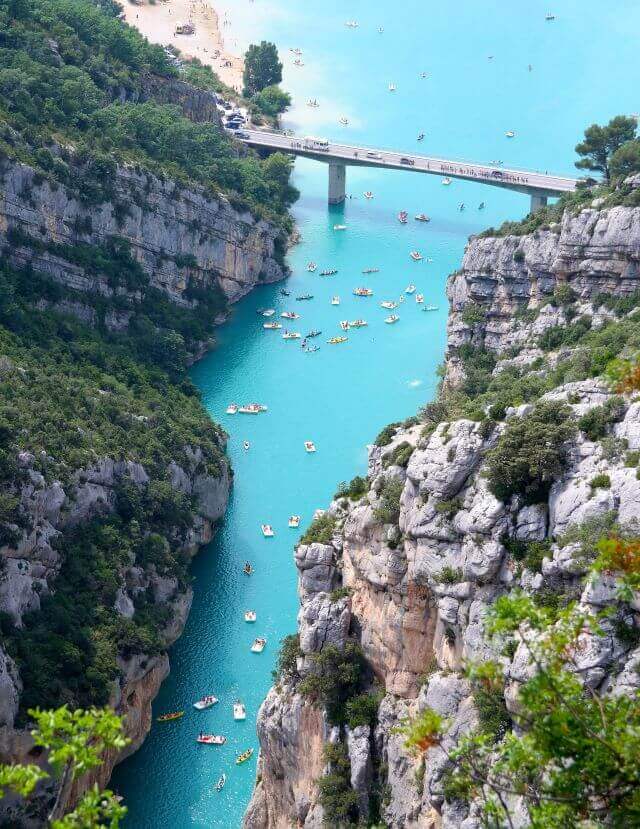 kayaks and paddleboats on blue water at the bottom of a canyon