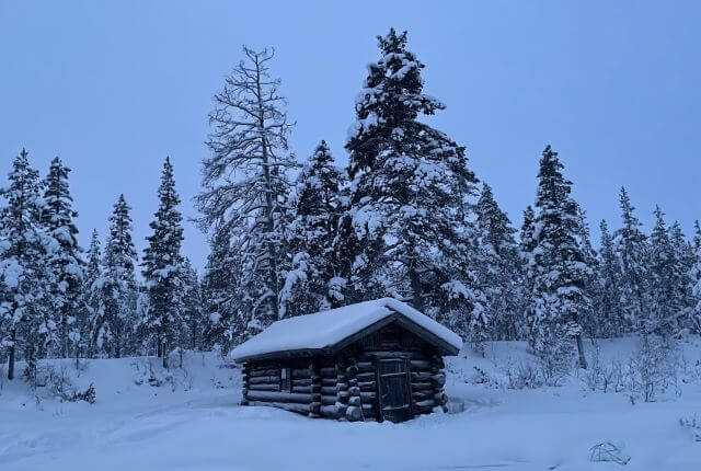 a small wooden hut covered in thick snow