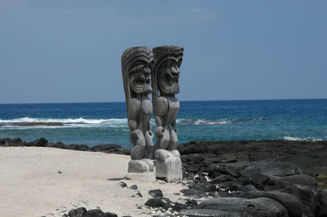 two carved statues facing the ocean