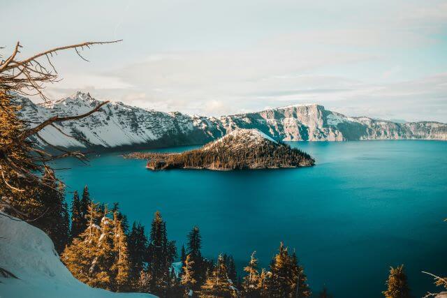 an island with snow in the middle of a blue lake