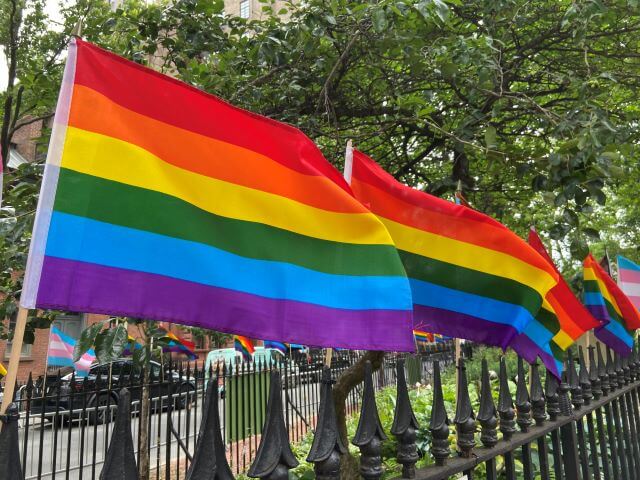 rainbow pride flags on a wrought iron fence