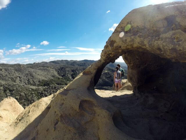 a stone arch over two hikers