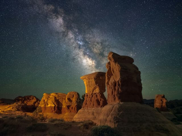 sculpted red rocks under a starry night sky