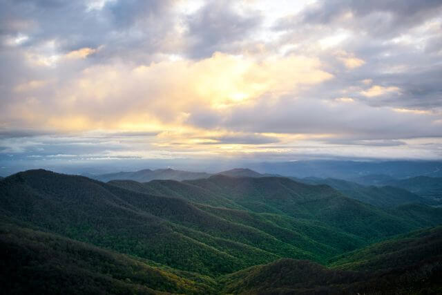 rows of green and blue mountains under a cloudy sky