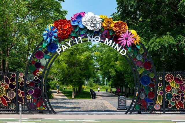 a flower-covered gate reading "Pay it no mind"